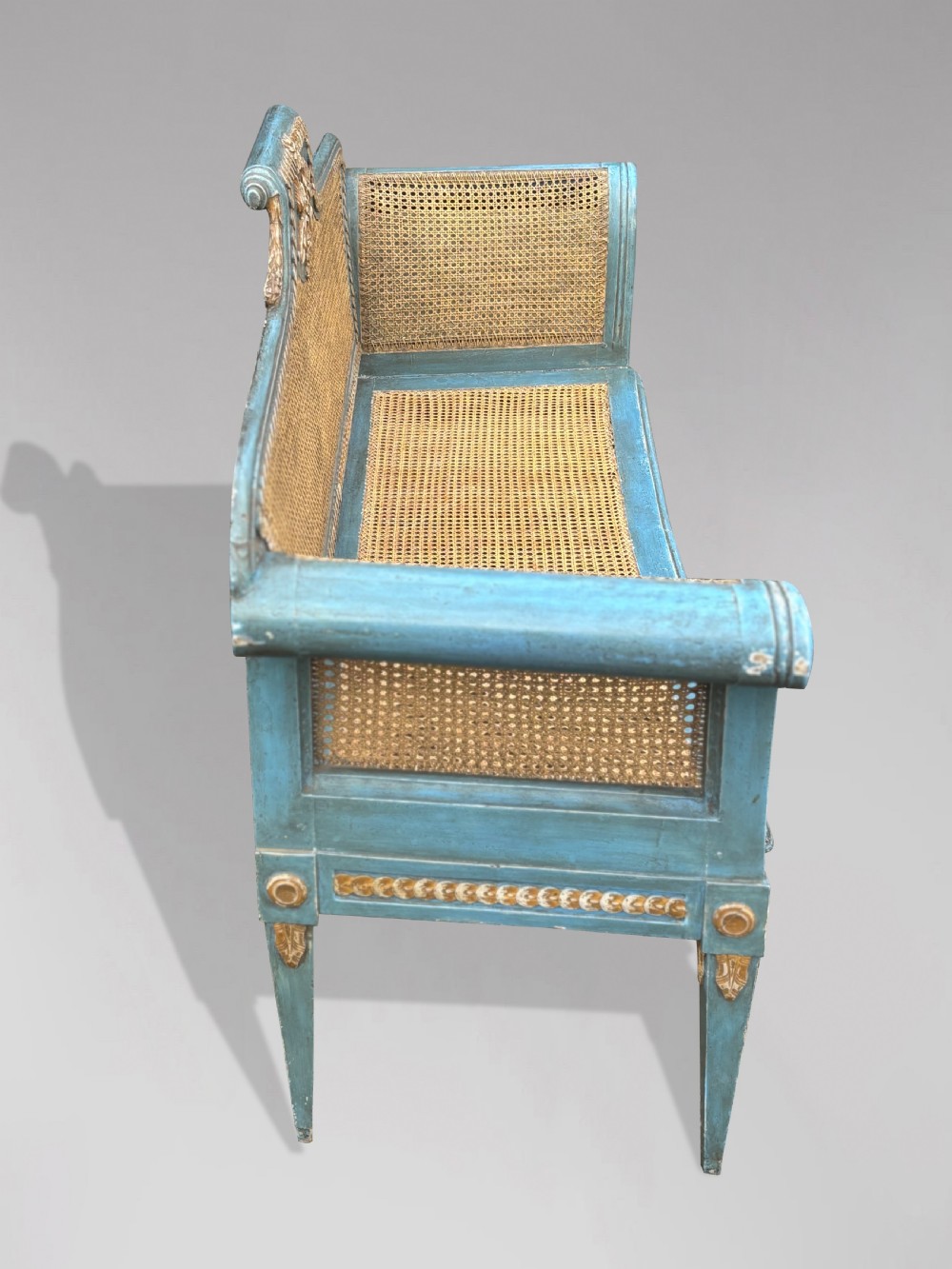 A late 19th-century Louis XVI style settee featuring blue painted trim with gold leaf details, woven cane seat and back panels, and six fluted legs. View XIII