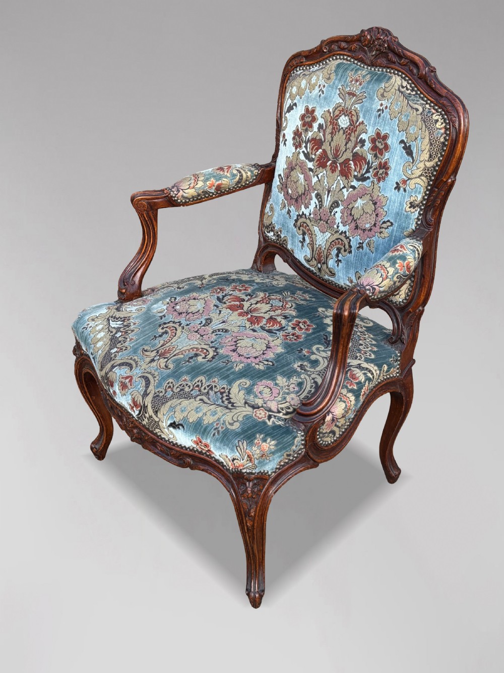 A set of four 19th-century French Louis XV style fauteuil armchairs featuring carved timber frames, cabriole legs, and blue floral upholstery. View X