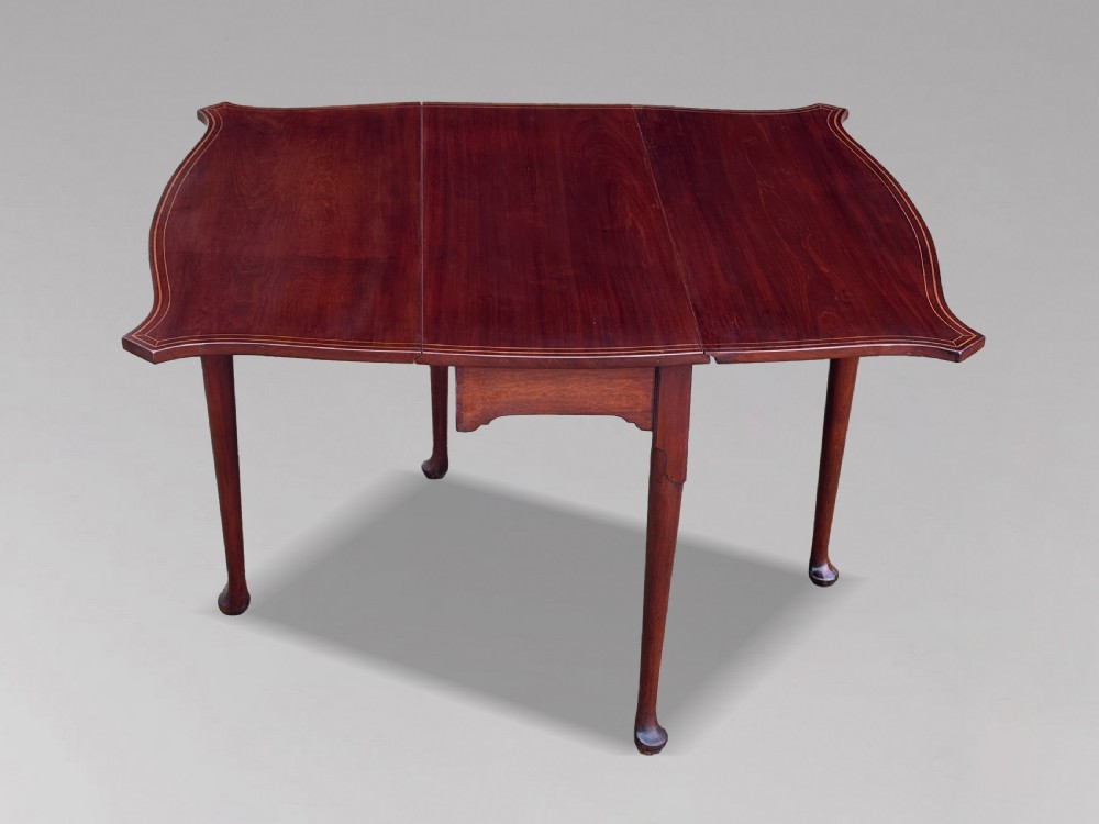 An 18th-century George III mahogany drop-leaf table featuring shaped corner edges with fine stringing inlay and slender legs terminating in pad feet. View II