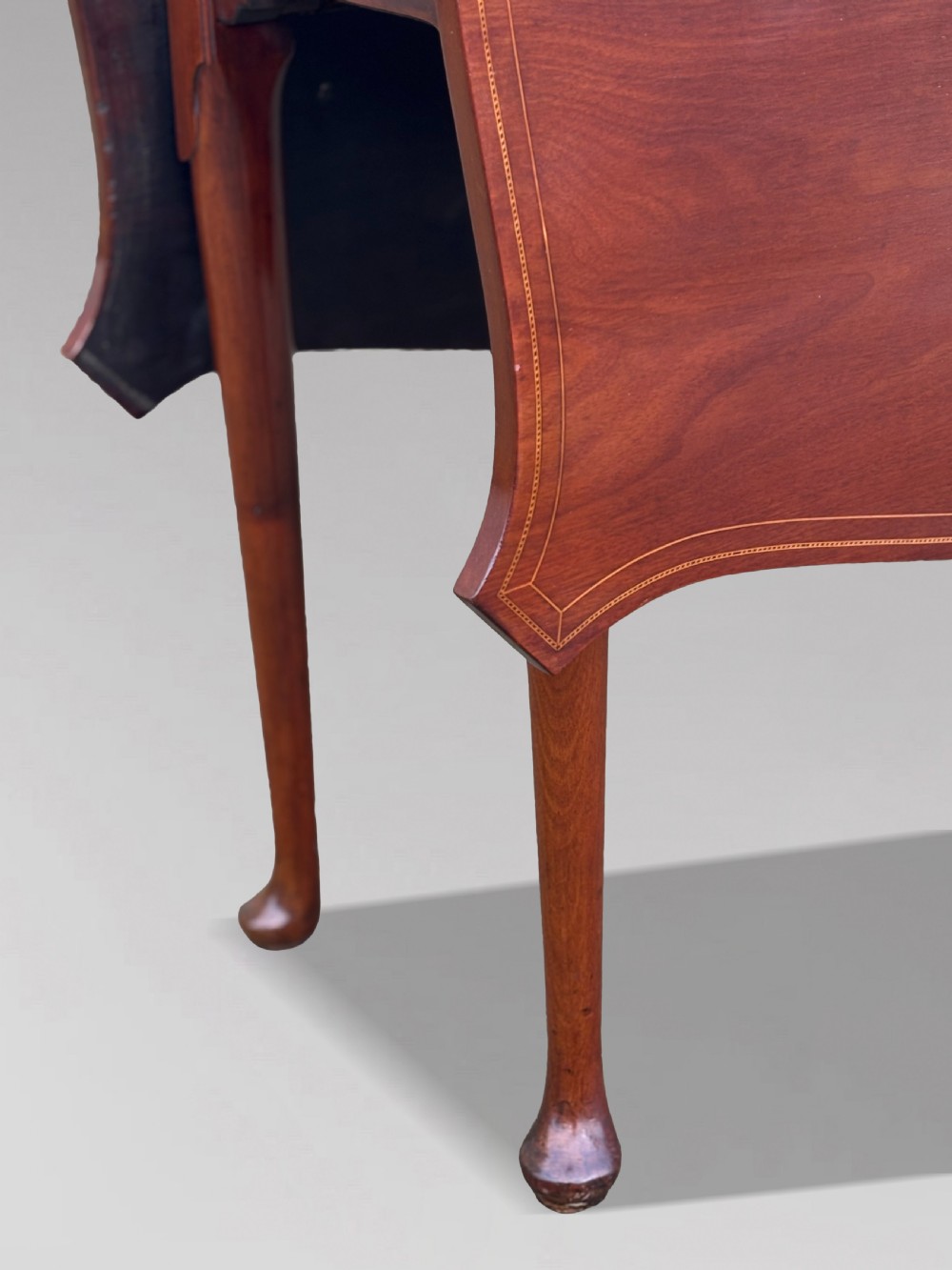 An 18th-century George III mahogany drop-leaf table featuring shaped corner edges with fine stringing inlay and slender legs terminating in pad feet. View V