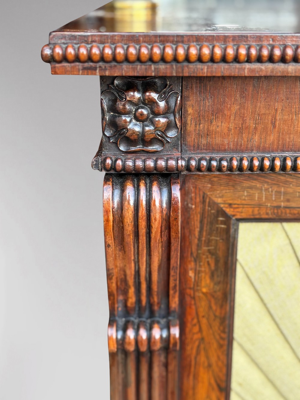 A Regency rosewood sideboard featuring three doors with sunburst pleated panels, a mirrored upper shelf supported by brass columns, and a pierced brass top gallery. View V