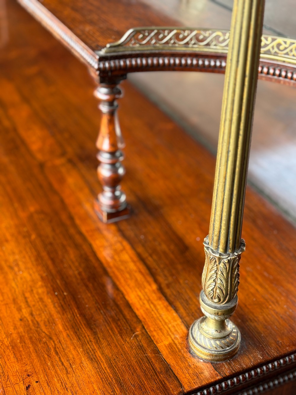 A Regency rosewood sideboard featuring three doors with sunburst pleated panels, a mirrored upper shelf supported by brass columns, and a pierced brass top gallery. View VIII