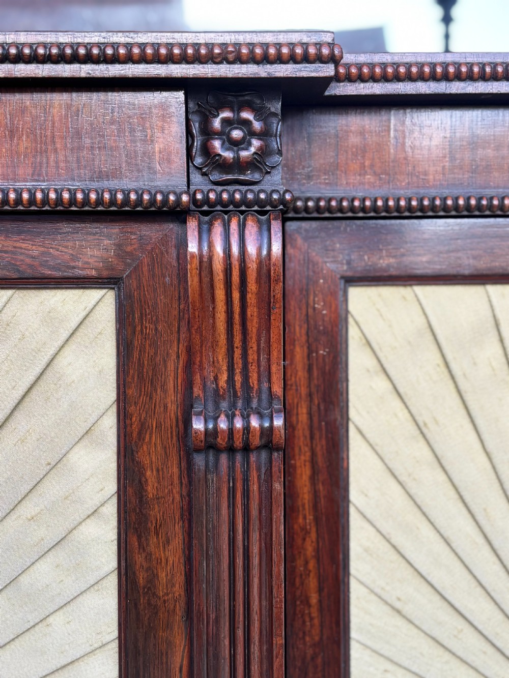 A Regency rosewood sideboard featuring three doors with sunburst pleated panels, a mirrored upper shelf supported by brass columns, and a pierced brass top gallery. View X