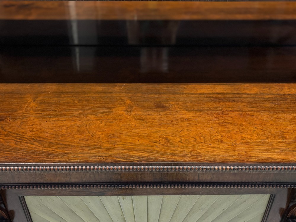 A Regency rosewood sideboard featuring three doors with sunburst pleated panels, a mirrored upper shelf supported by brass columns, and a pierced brass top gallery. View XII