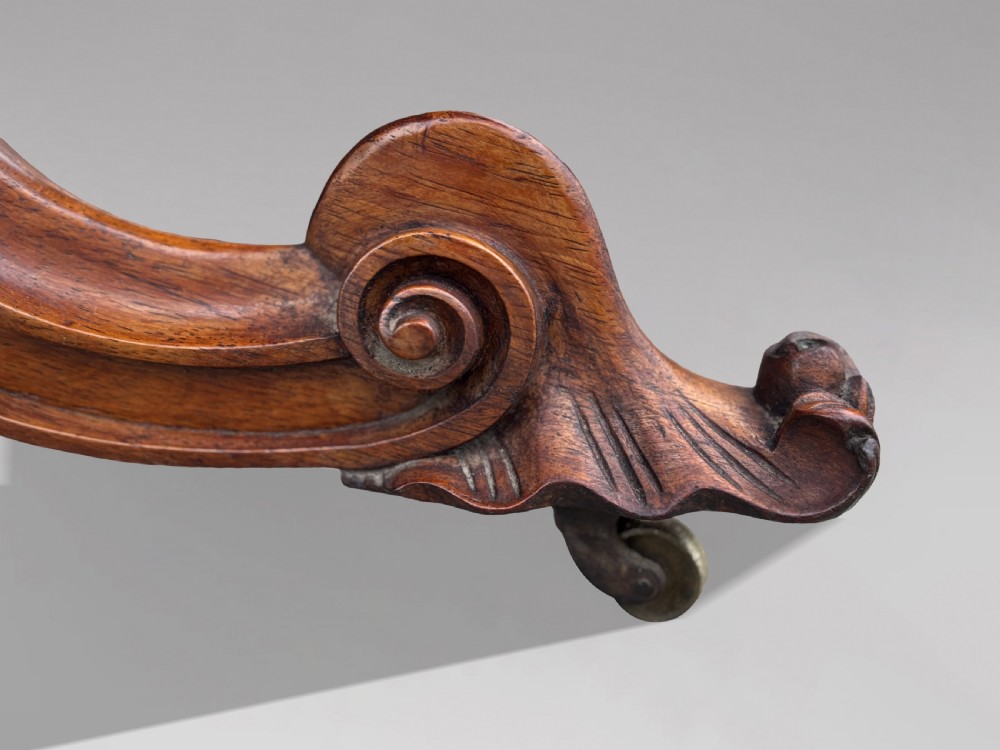 A 19th-century Victorian burr walnut centre table featuring a serpentine top with central floral marquetry and carved scroll legs on castors. View III