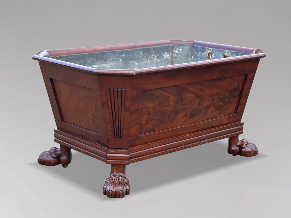 An early 19th-century Regency mahogany sarcophagus-shaped wine cooler featuring carved paw feet, fluted corner pilasters, and a metal liner.