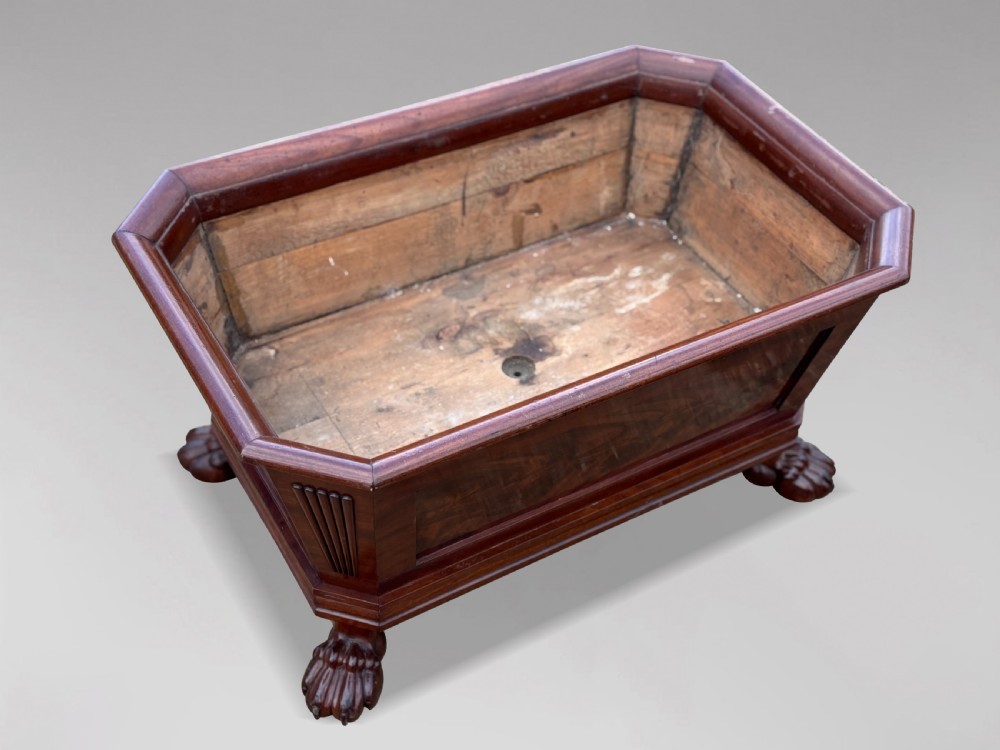 An early 19th-century Regency mahogany sarcophagus-shaped wine cooler featuring carved paw feet, fluted corner pilasters, and a metal liner. View IV