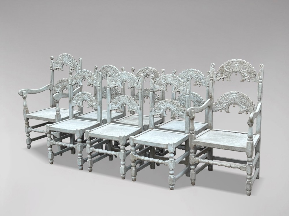 A set of eight light grey painted carved oak dining chairs featuring arched openwork backrests and turned legs.