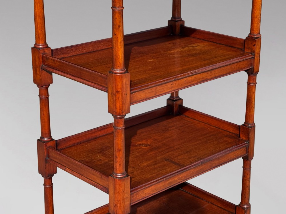 A four-tier George IV mahogany whatnot featuring a sloped top reading surface, turned wooden upright supports, and brass castors at the feet. View III