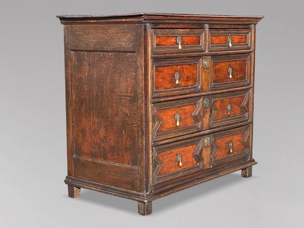 A 17th-century Charles II oak chest of drawers featuring geometric mitred mouldings, two short drawers over three long drawers, and brass teardrop handles. View II