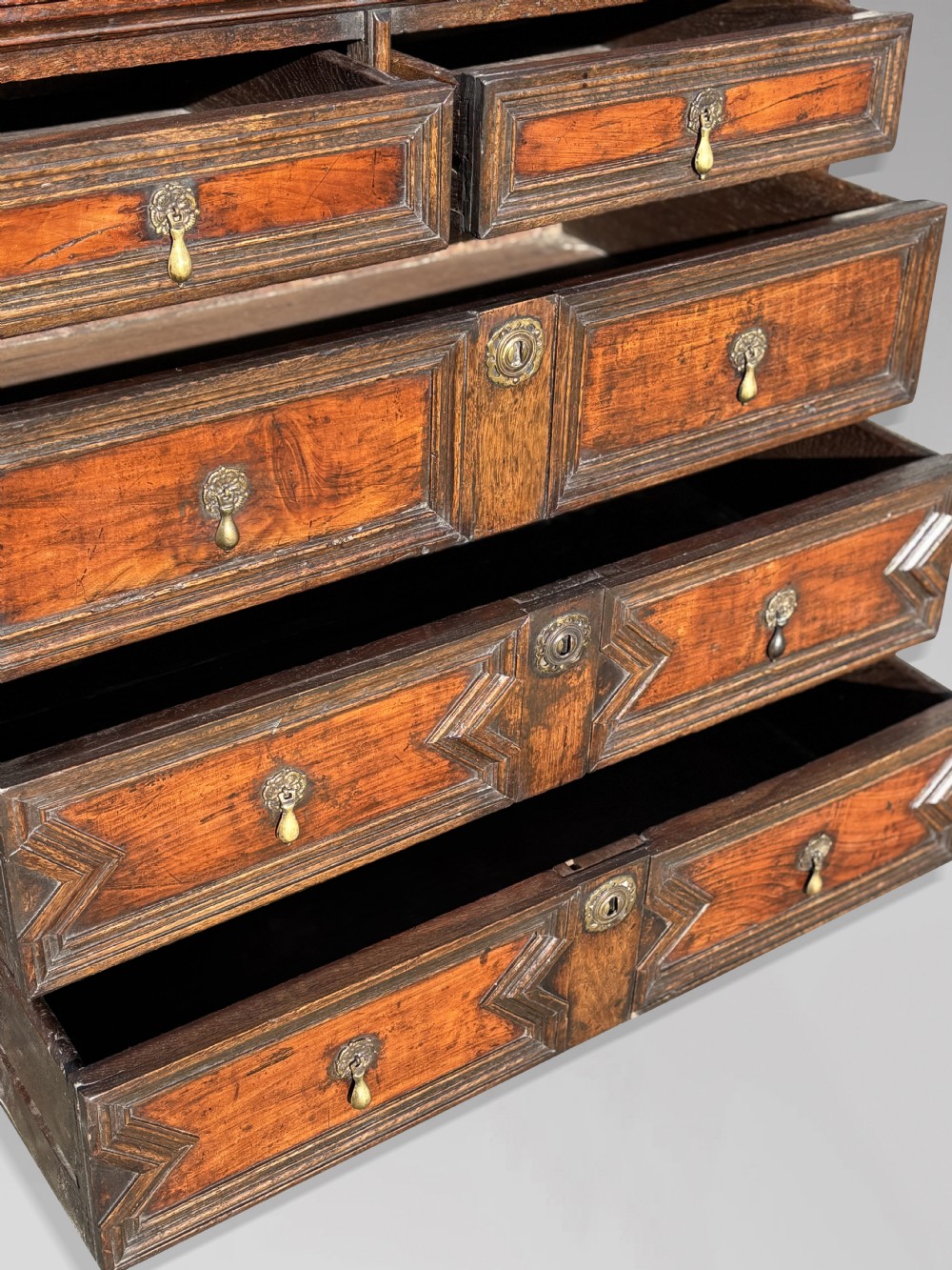 A 17th-century Charles II oak chest of drawers featuring geometric mitred mouldings, two short drawers over three long drawers, and brass teardrop handles. View V