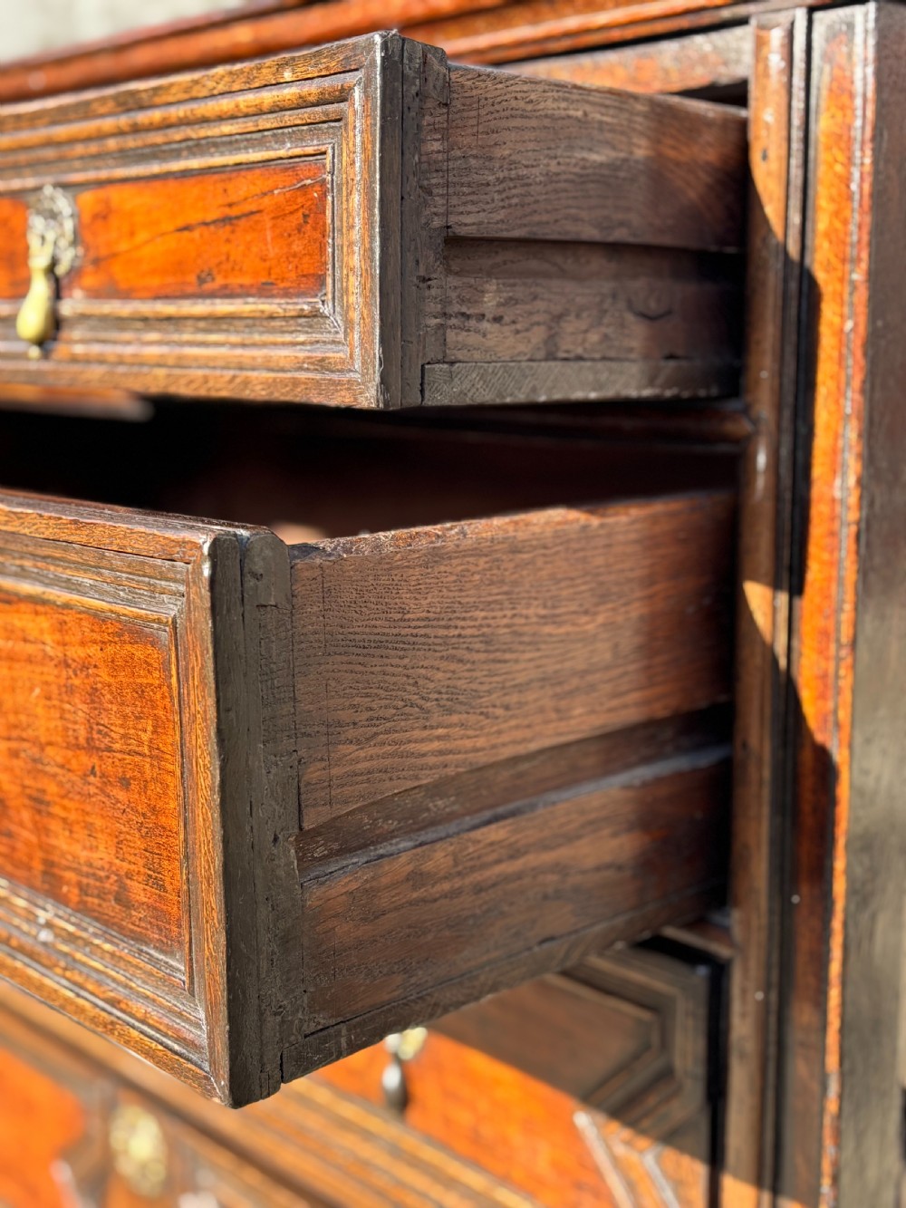 A 17th-century Charles II oak chest of drawers featuring geometric mitred mouldings, two short drawers over three long drawers, and brass teardrop handles. View VIII