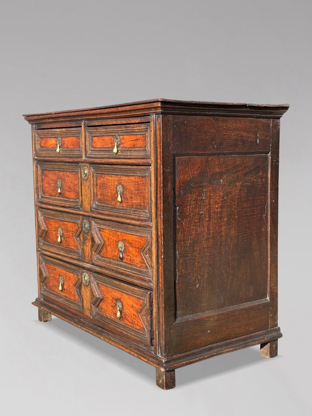 A 17th-century Charles II oak chest of drawers featuring geometric mitred mouldings, two short drawers over three long drawers, and brass teardrop handles. View X