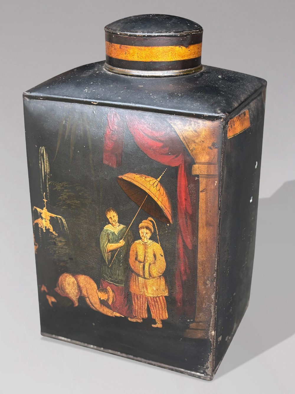 A set of three black rectangular antique toleware tea canisters hand-painted with detailed Chinoiserie figures and red drapery scenes. View III