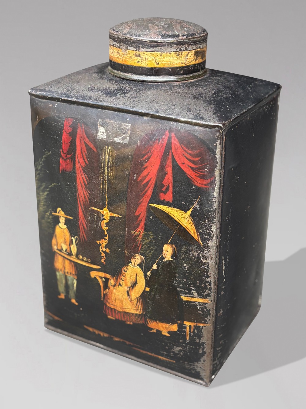 A set of three black rectangular antique toleware tea canisters hand-painted with detailed Chinoiserie figures and red drapery scenes. View IV