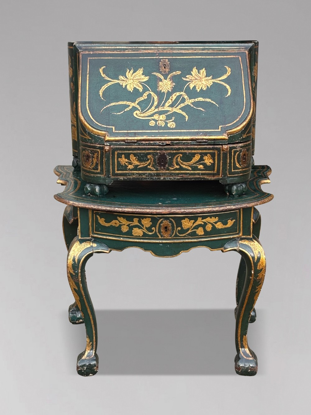 An 18th-century Venetian dark green lacquered travelling bureau with gilded floral scrollwork and fall-front writing flap resting on a matching cabriole-leg stand. View VII