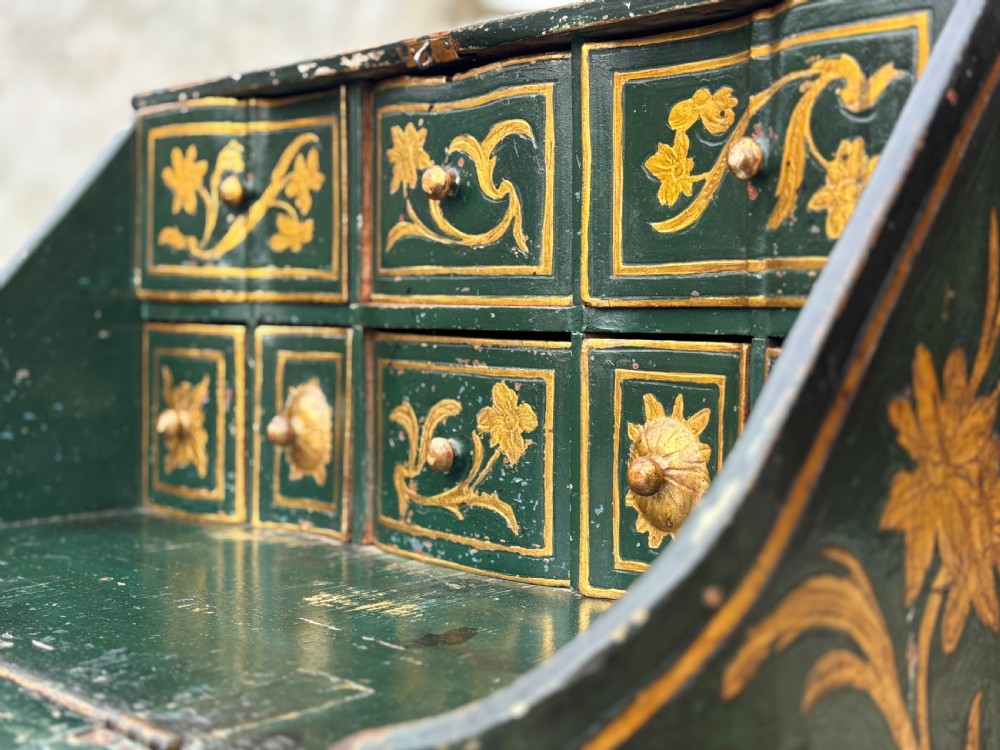 An 18th-century Venetian dark green lacquered travelling bureau with gilded floral scrollwork and fall-front writing flap resting on a matching cabriole-leg stand. View X