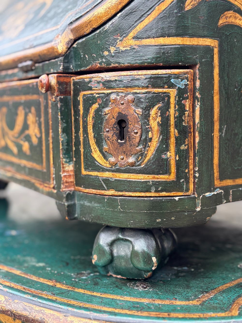 An 18th-century Venetian dark green lacquered travelling bureau with gilded floral scrollwork and fall-front writing flap resting on a matching cabriole-leg stand. View XI