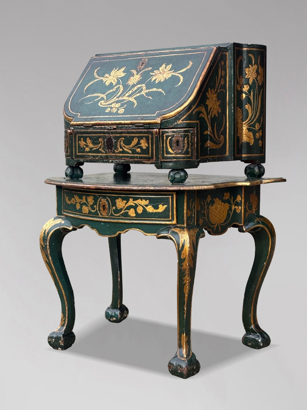 An 18th-century Venetian dark green lacquered travelling bureau with gilded floral scrollwork and fall-front writing flap resting on a matching cabriole-leg stand. View XVI