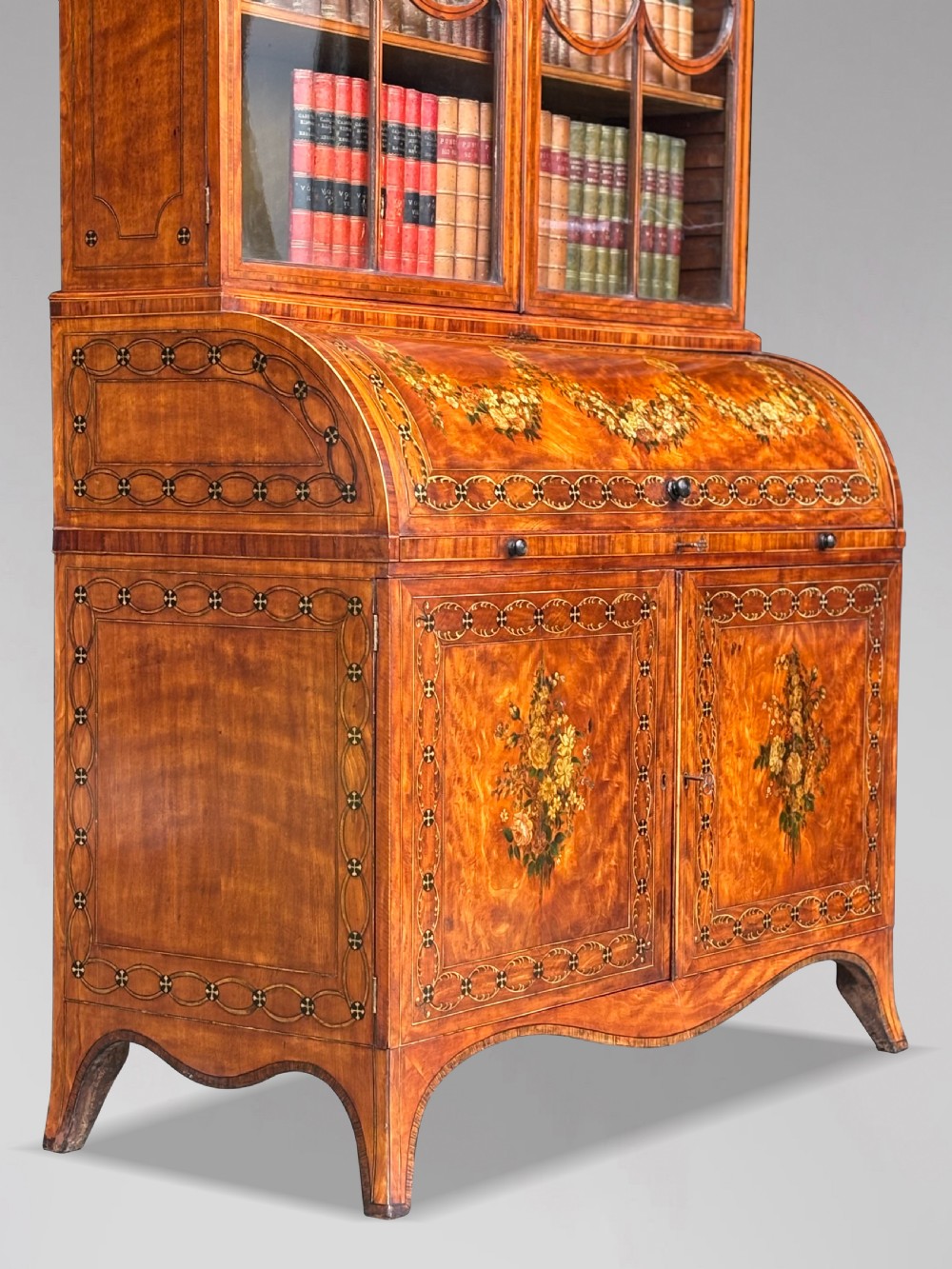 An 18th-century George III satinwood bureau bookcase featuring a glazed upper display cabinet above a cylinder writing section and two inlaid lower doors. View VI