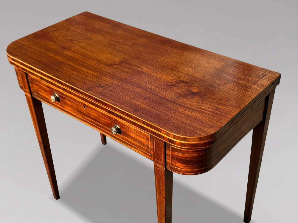 An 18th-century George III mahogany fold-over tea table featuring fine string inlay, a frieze drawer with brass handles, and tapered legs. View III