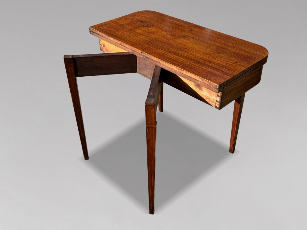 An 18th-century George III mahogany fold-over tea table featuring fine string inlay, a frieze drawer with brass handles, and tapered legs. View IV