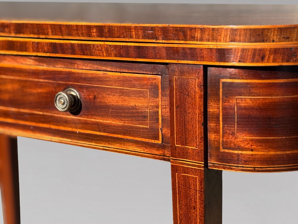 An 18th-century George III mahogany fold-over tea table featuring fine string inlay, a frieze drawer with brass handles, and tapered legs. View VI