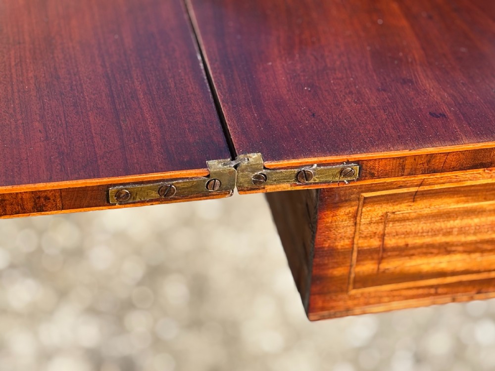 An 18th-century George III mahogany fold-over tea table featuring fine string inlay, a frieze drawer with brass handles, and tapered legs. View VII