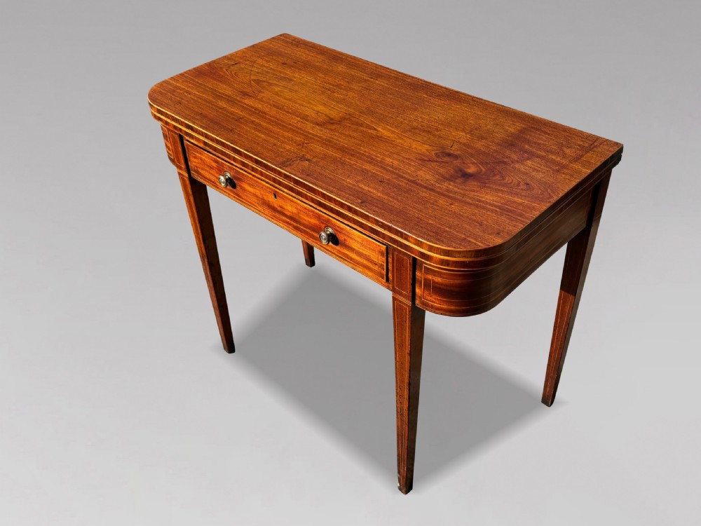An 18th-century George III mahogany fold-over tea table featuring fine string inlay, a frieze drawer with brass handles, and tapered legs. View XI