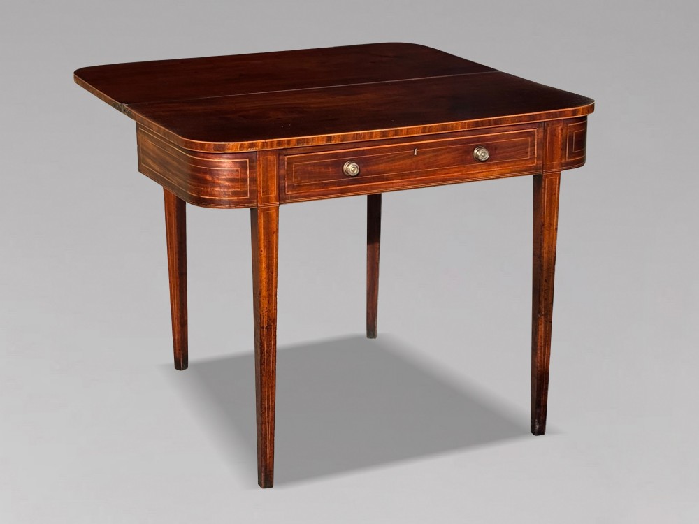 An 18th-century George III mahogany fold-over tea table featuring fine string inlay, a frieze drawer with brass handles, and tapered legs. View XII