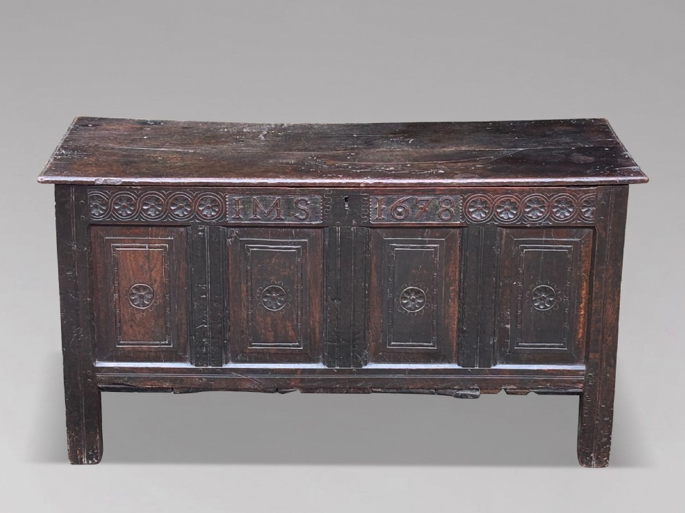 A seventeenth-century dark oak joined coffer with four carved panelled sections, a carved top rail dated 1678, and carved initials IMS.