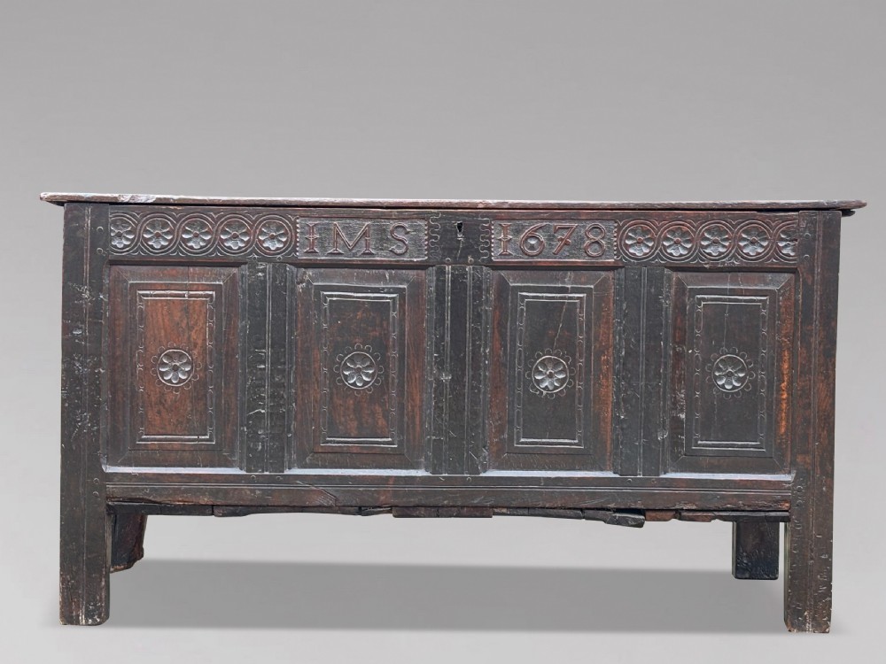 A seventeenth-century dark oak joined coffer with four carved panelled sections, a carved top rail dated 1678, and carved initials IMS. View II
