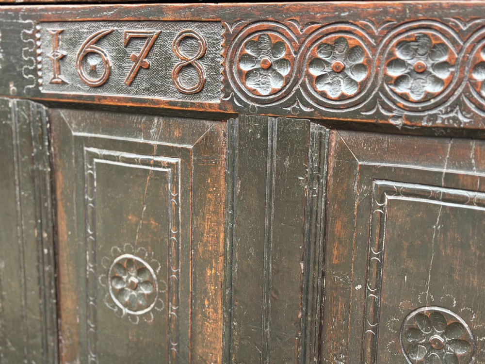 A seventeenth-century dark oak joined coffer with four carved panelled sections, a carved top rail dated 1678, and carved initials IMS. View VI
