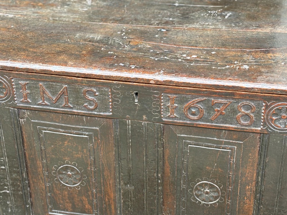 A seventeenth-century dark oak joined coffer with four carved panelled sections, a carved top rail dated 1678, and carved initials IMS. View VIII