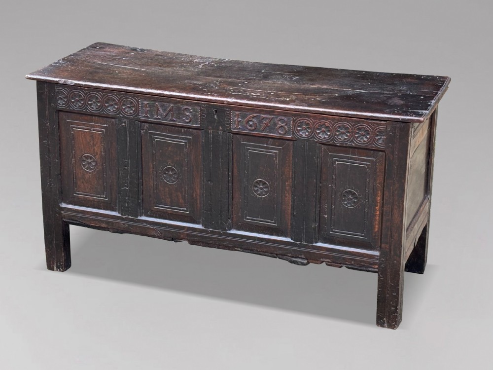 A seventeenth-century dark oak joined coffer with four carved panelled sections, a carved top rail dated 1678, and carved initials IMS. View X