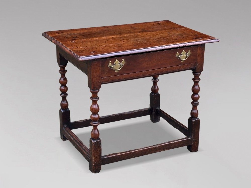 An early 18th-century George I period walnut lowboy side table featuring a single drawer with brass handles, turned legs, and a low box stretcher.