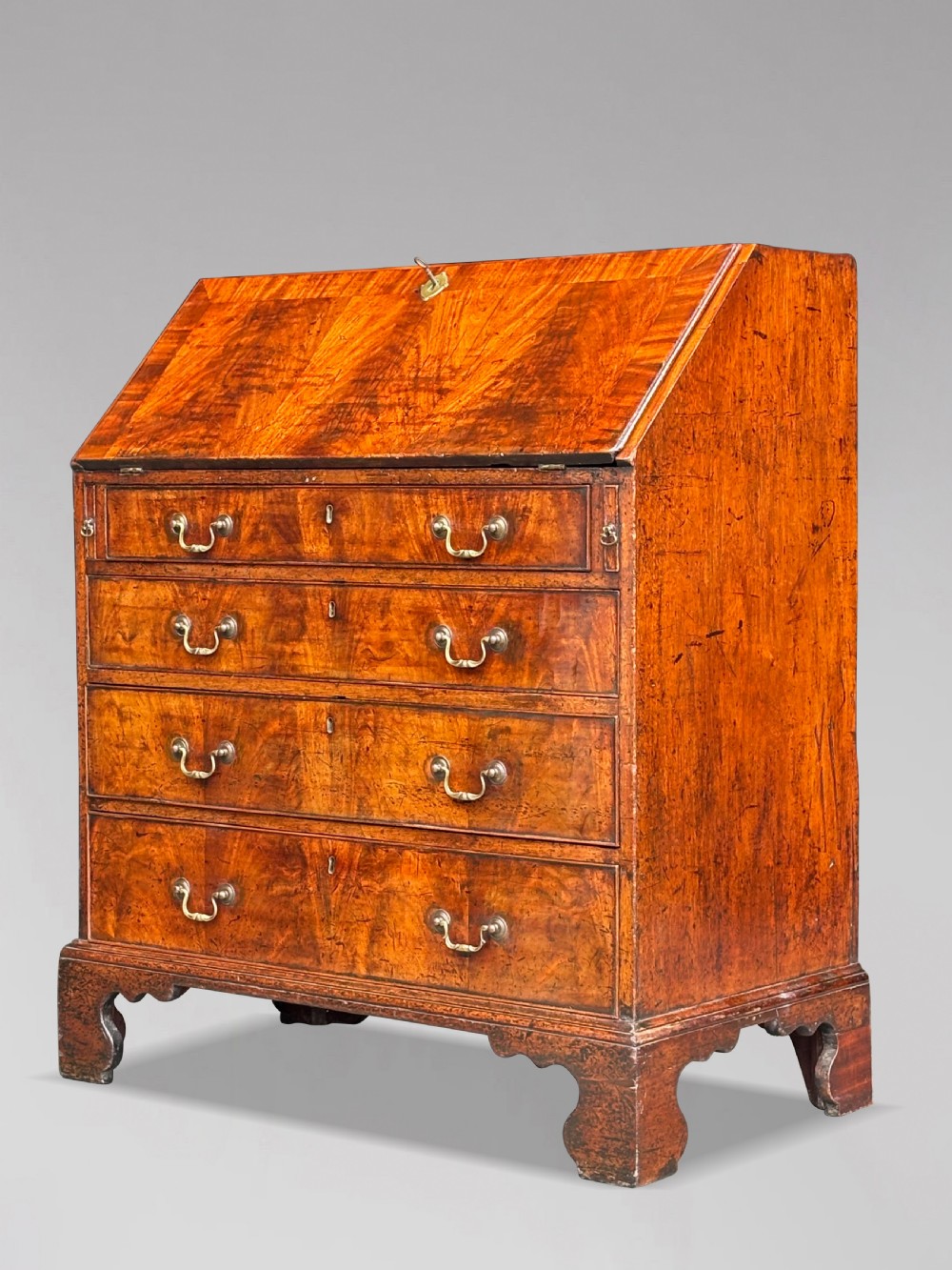 An 18th-century George III mahogany slant-front bureau featuring four graduated drawers with brass swan-neck handles and shaped bracket feet. View II