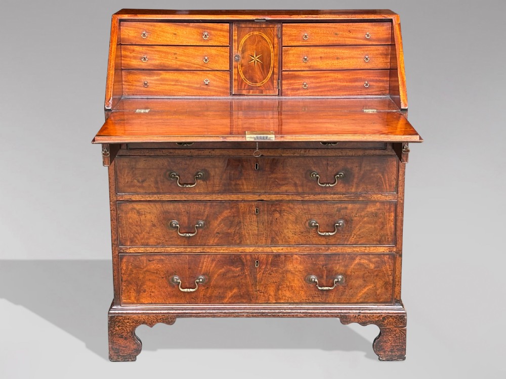 An 18th-century George III mahogany slant-front bureau featuring four graduated drawers with brass swan-neck handles and shaped bracket feet. View V