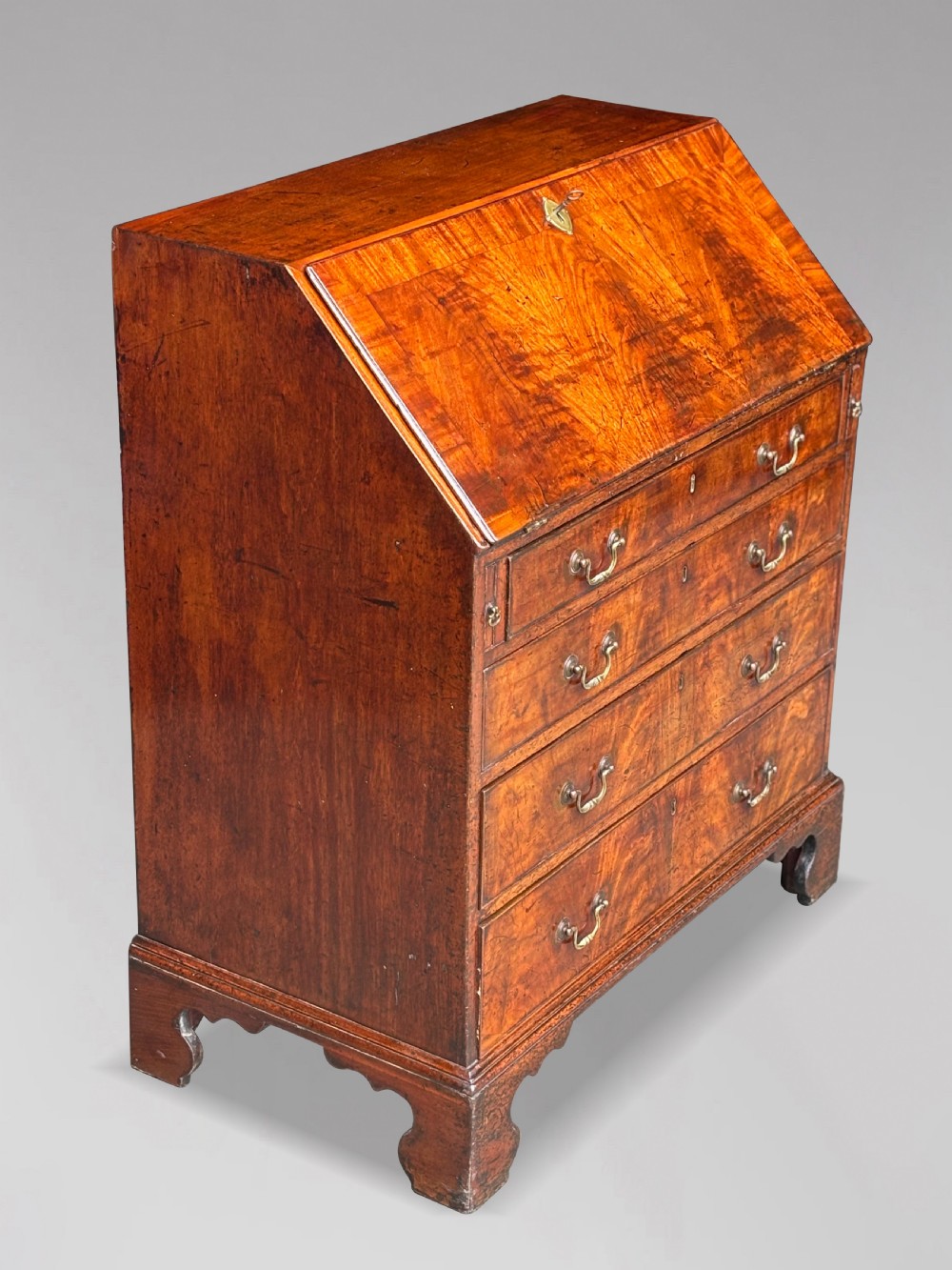 An 18th-century George III mahogany slant-front bureau featuring four graduated drawers with brass swan-neck handles and shaped bracket feet. View IX