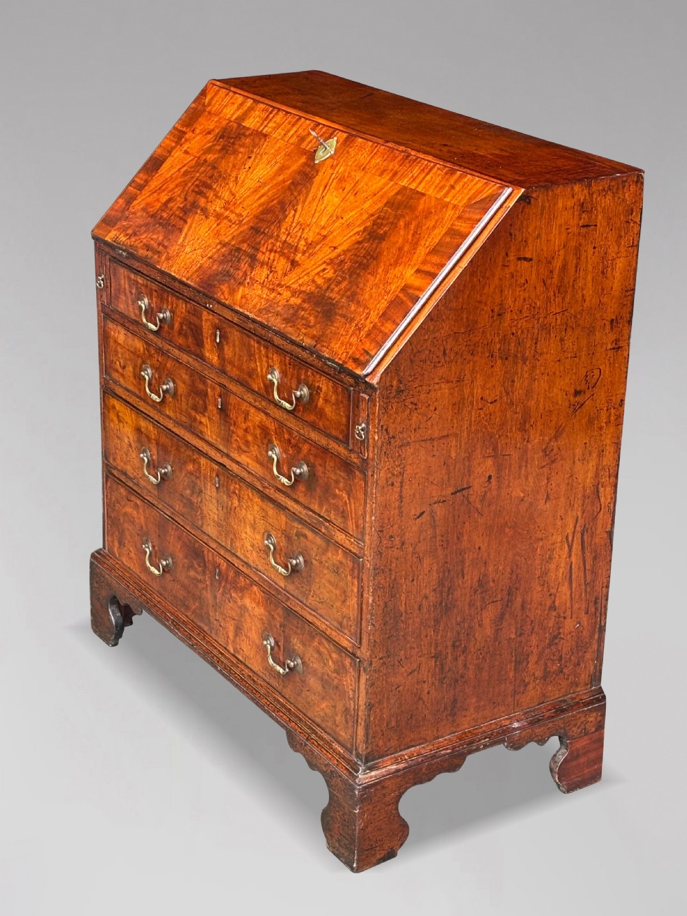 An 18th-century George III mahogany slant-front bureau featuring four graduated drawers with brass swan-neck handles and shaped bracket feet. View X