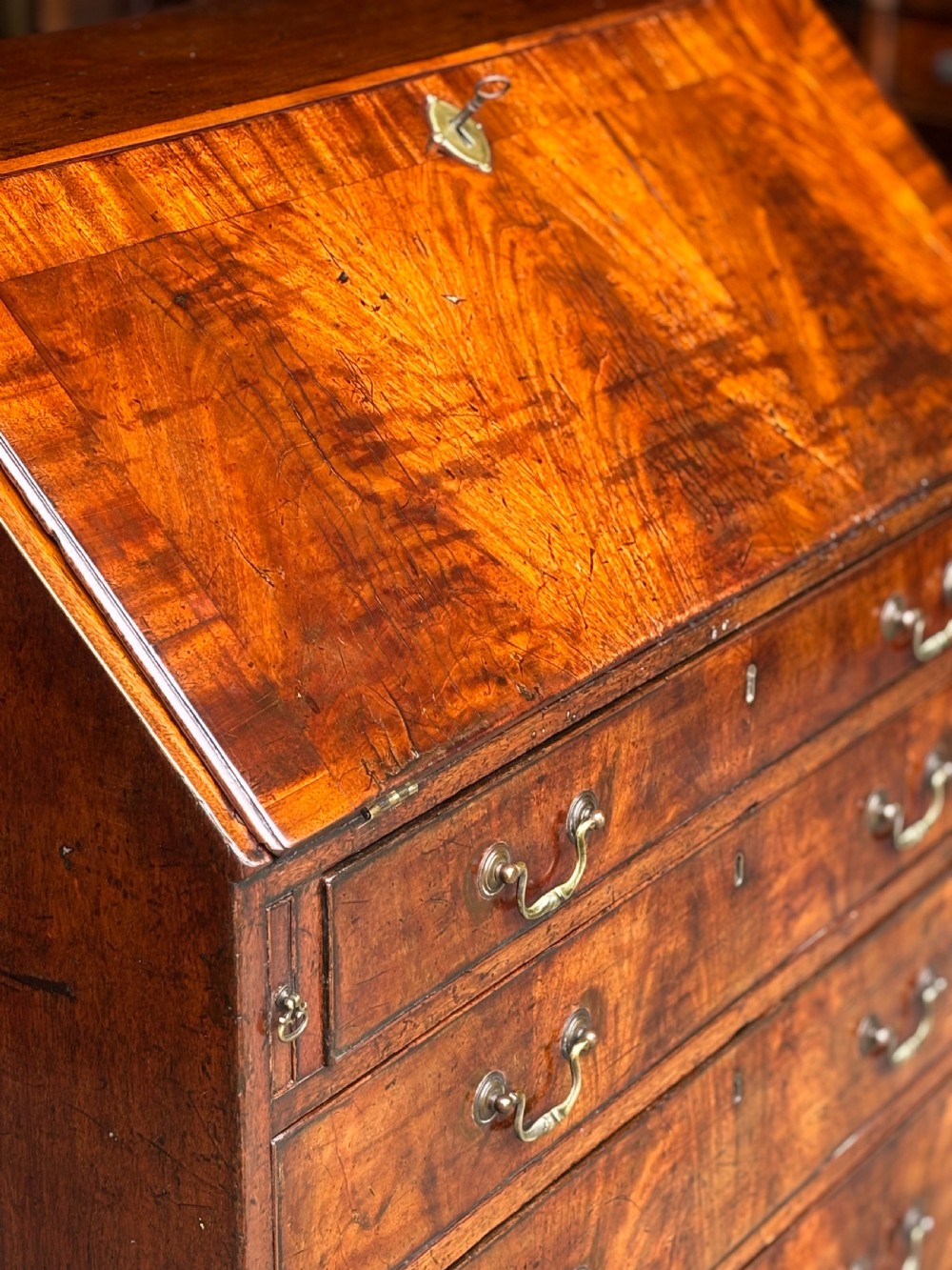 An 18th-century George III mahogany slant-front bureau featuring four graduated drawers with brass swan-neck handles and shaped bracket feet. View XII