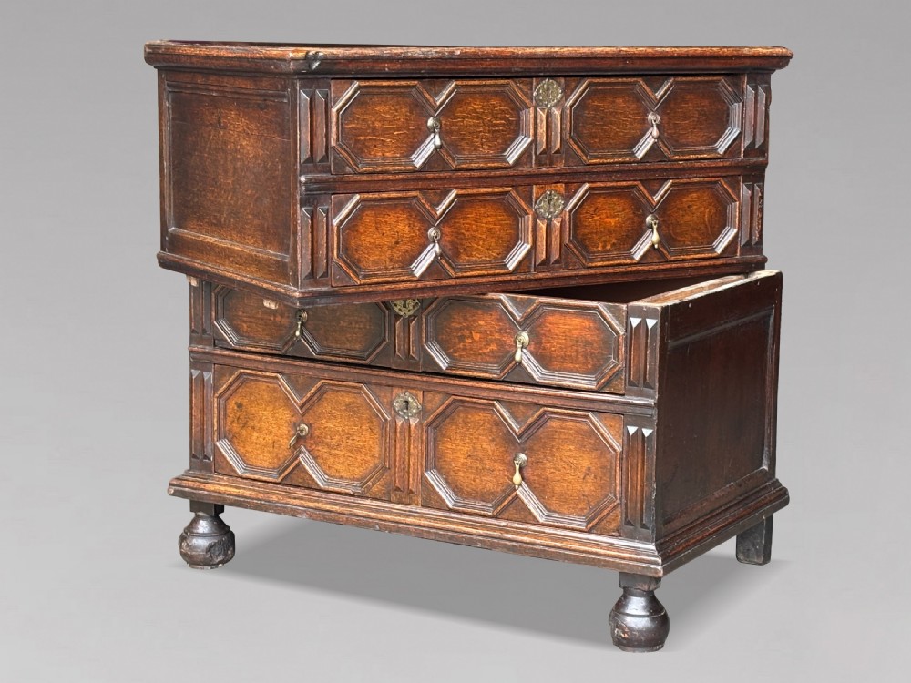A seventeenth-century Charles II oak chest of drawers featuring four geometric panelled drawers with brass teardrop handles, resting on turned bun feet. View IV