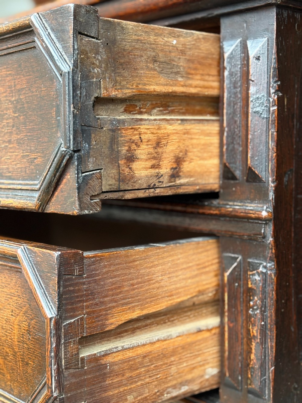 A seventeenth-century Charles II oak chest of drawers featuring four geometric panelled drawers with brass teardrop handles, resting on turned bun feet. View IX