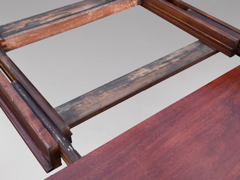A 19th-century mahogany extending dining table featuring a polished rectangular top with rounded corners, supported by four heavy turned legs on brass castors. View IV
