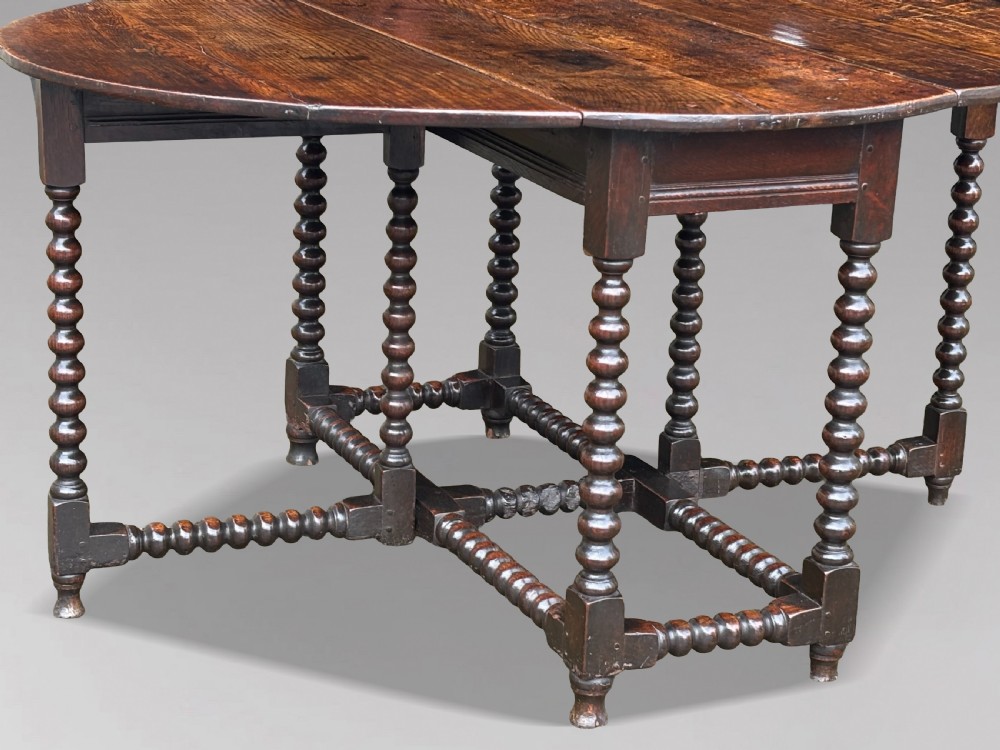 A 17th-century Charles II dark oak gateleg table featuring an oval drop-leaf top supported by bobbin-turned legs and stretchers. View II