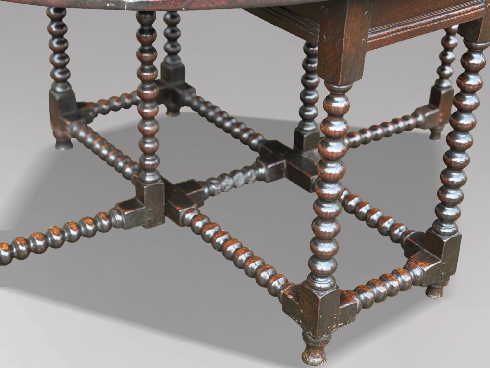 A 17th-century Charles II dark oak gateleg table featuring an oval drop-leaf top supported by bobbin-turned legs and stretchers. View III