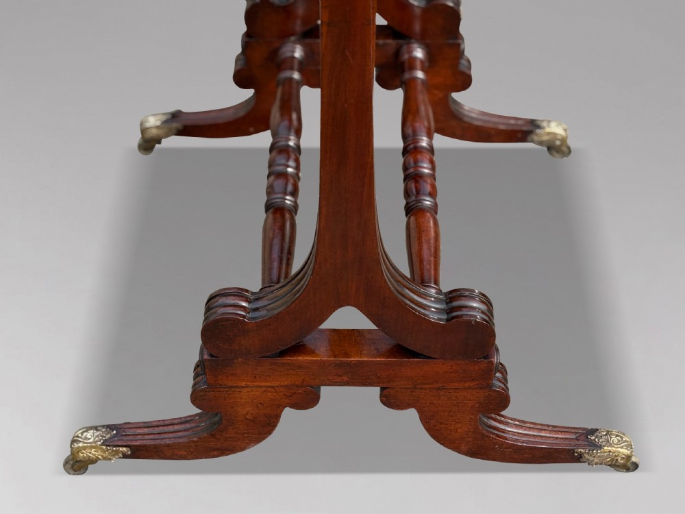 A 19th-century William IV mahogany cheval mirror featuring a rectangular swivel glass plate, dual brass candle sconces, turned stretchers, and splayed legs with brass claw feet on castors. View V