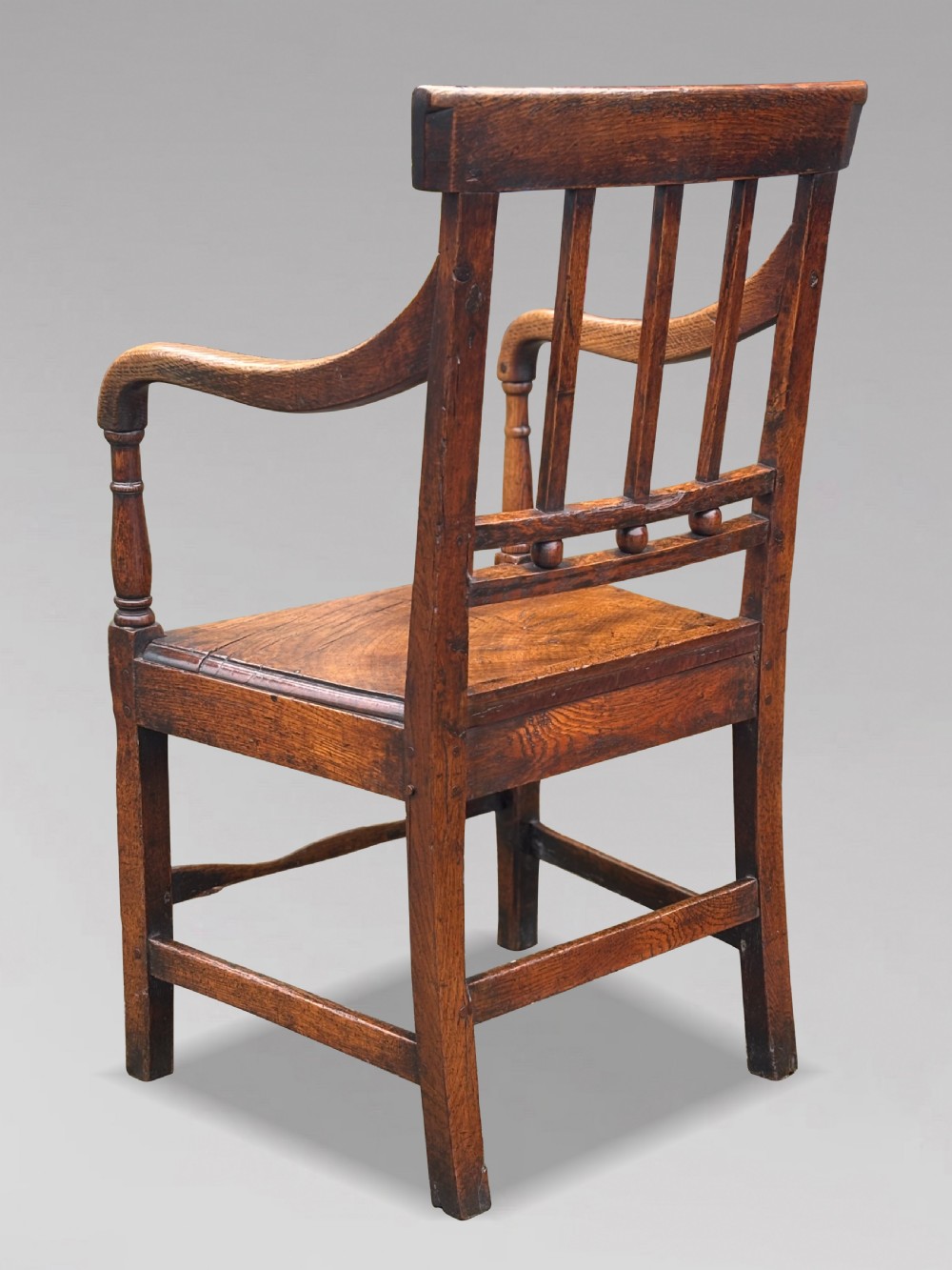 An 18th-century George III elm country armchair featuring a solid timber seat, curved arms, vertical back splats, and square legs. View III