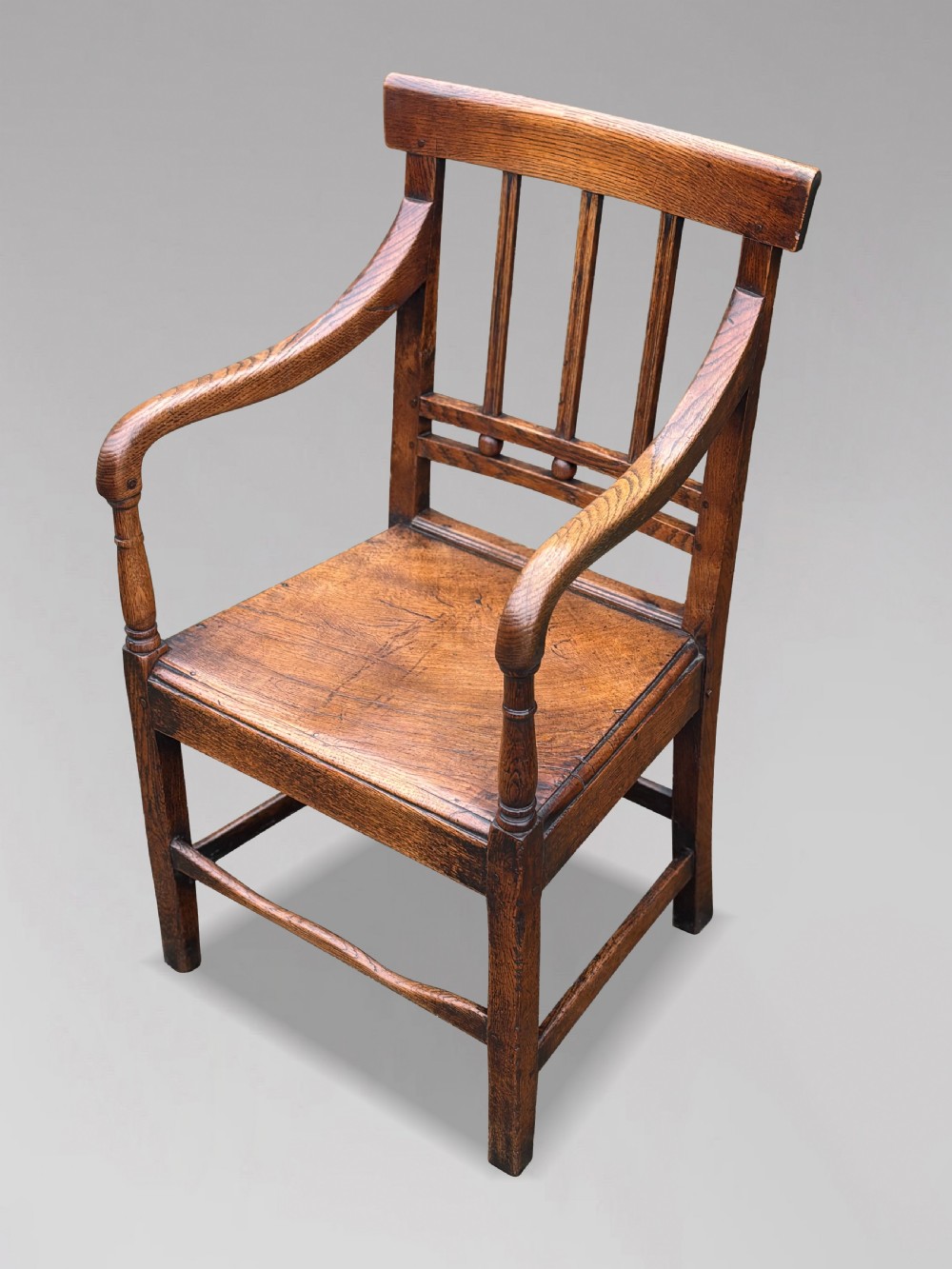 An 18th-century George III elm country armchair featuring a solid timber seat, curved arms, vertical back splats, and square legs. View IV