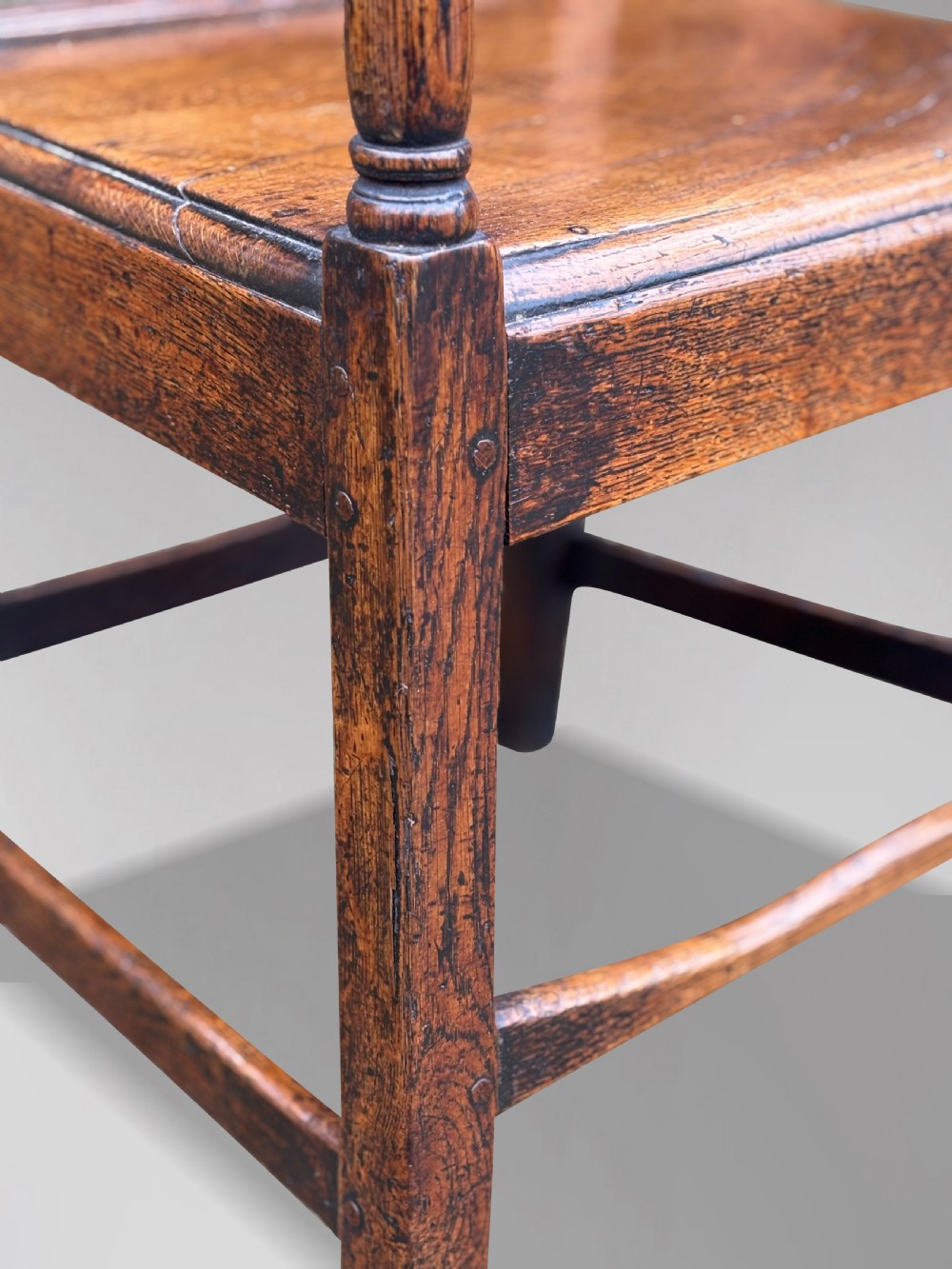 An 18th-century George III elm country armchair featuring a solid timber seat, curved arms, vertical back splats, and square legs. View VII